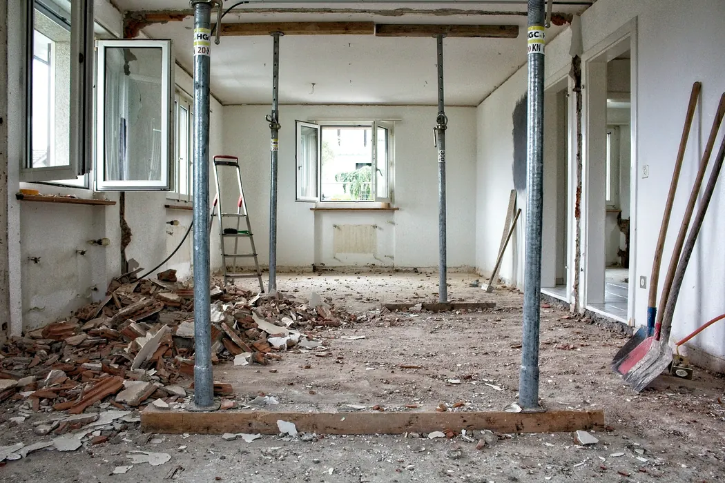 Before (stock photo): a room stripped back to bare walls with temporary steel props