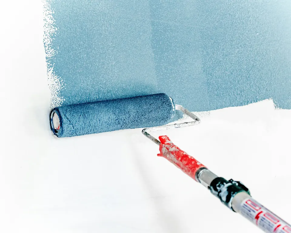 Paint roller applying a fresh coat of paint to a wall